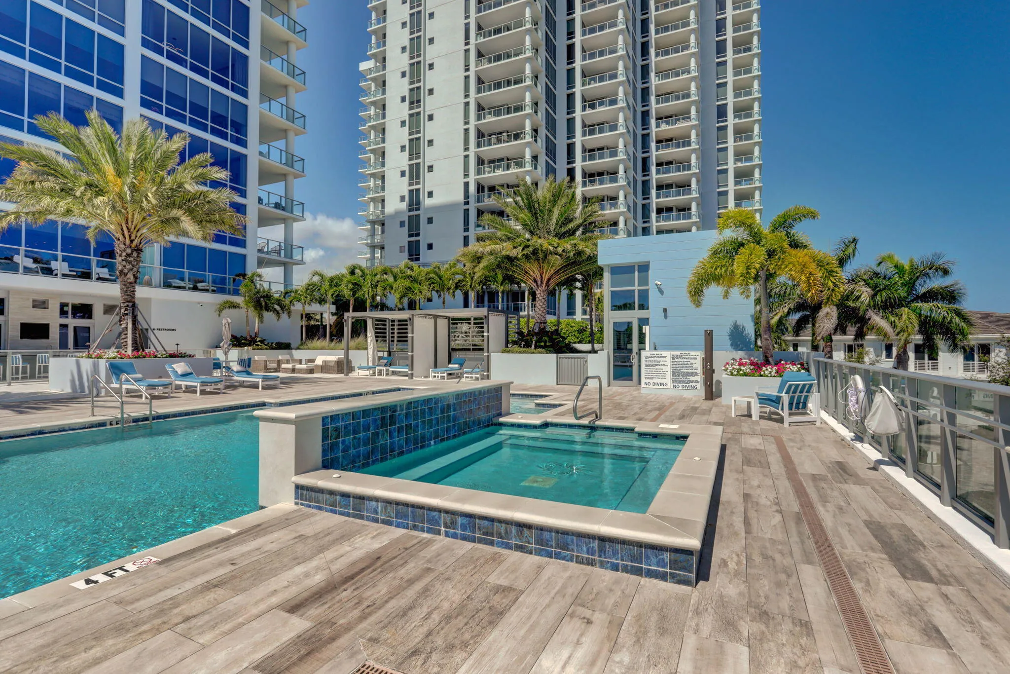 Resort-style pool area featuring a rectangular swimming pool, integrated spa, and wood-finish decking