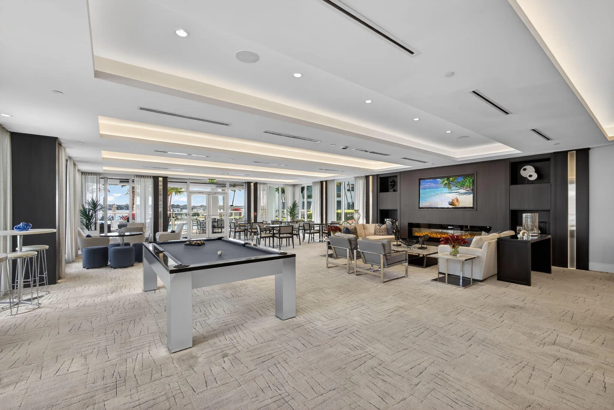 Recessed lighting, wood-finish accent walls, and a built-in fireplace feature in this expansive common area