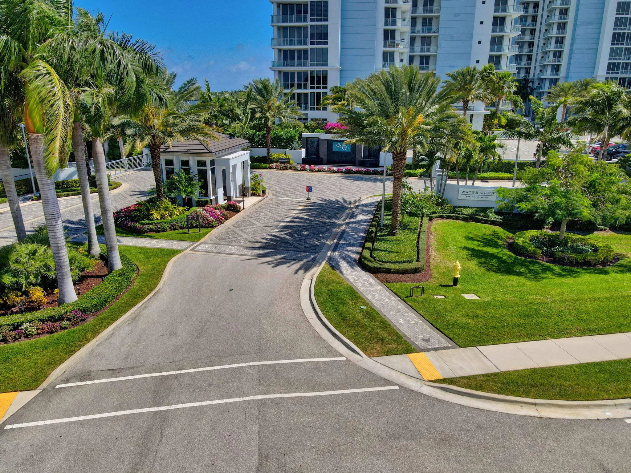 Gated entry featuring a 24/7 manned guardhouse, extensive landscaping, mature palm trees and security systems.