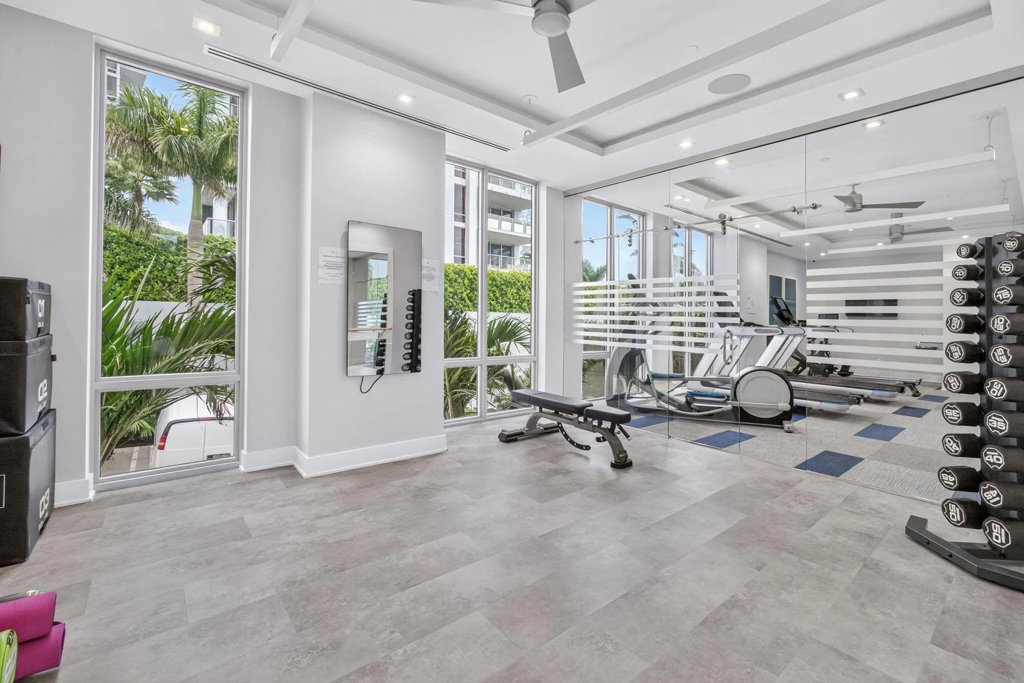 Floor-to-ceiling Sunny windows, modern recessed lighting, tray ceiling, full-height mirrored wall, and light-toned flooring