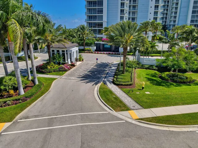 Gated entry featuring a 24/7 manned guardhouse, extensive landscaping, mature palm trees and security systems.