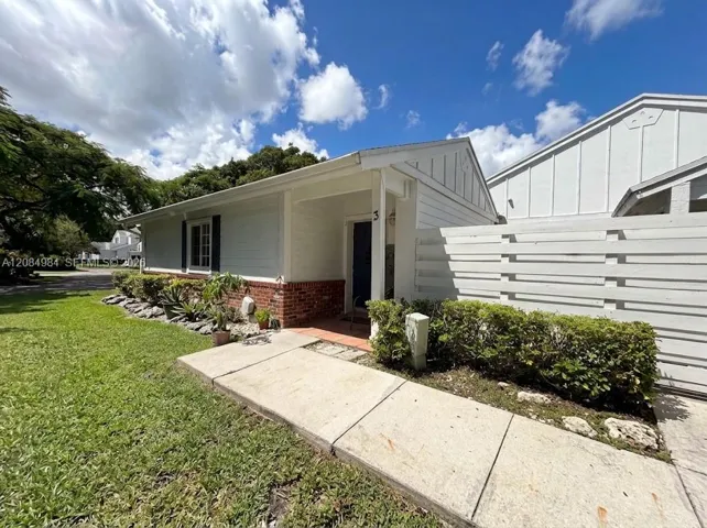 home exterior featuring a front entrance, well-maintained lawn, and paved driveway.