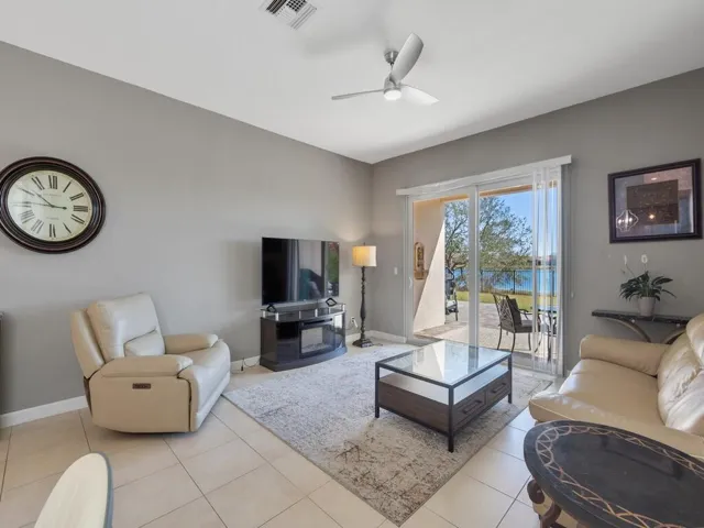 Spacious living area featuring tile flooring, a modern ceiling fan, and sliding glass doors opening to an outdoor patio