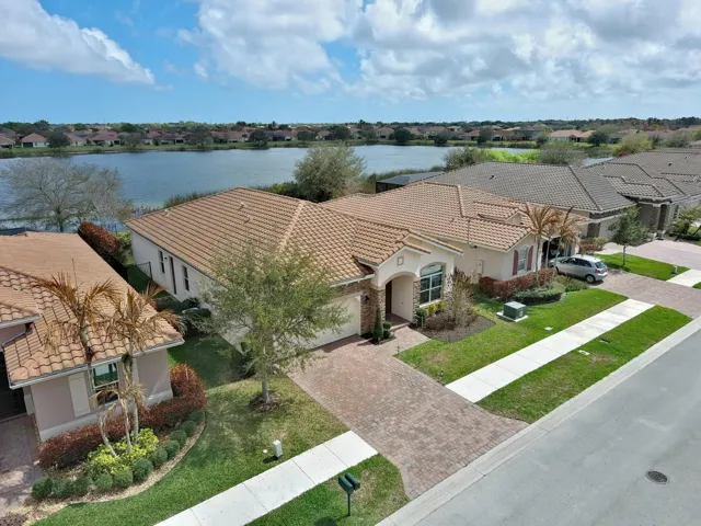Mediterranean-style residence featuring a tile roof, paver driveway, manicured landscaping, and a waterfront location