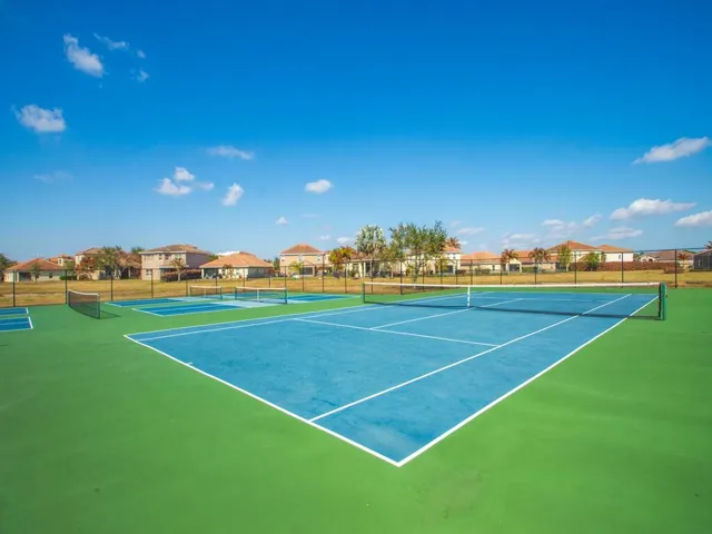 Multi-court facility featuring blue and green hard courts, white court lines, and black chain-link fencing
