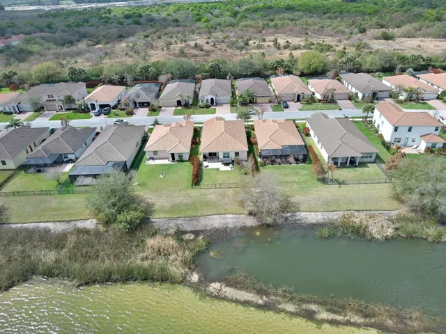 Mediterranean-style residence featuring a tile roof, paver driveway, manicured landscaping, and a waterfront location