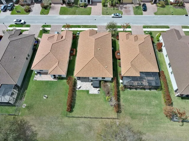 Mediterranean-style residence featuring a tile roof, paver driveway, manicured landscaping, and a waterfront location