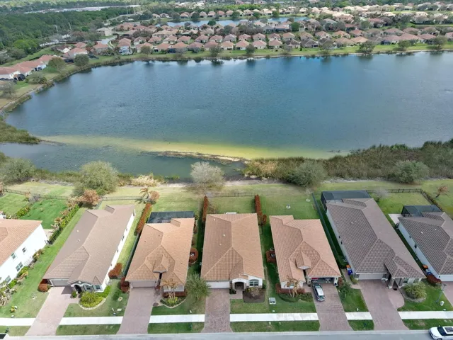 Mediterranean-style residence featuring a tile roof, paver driveway, manicured landscaping, and a waterfront location