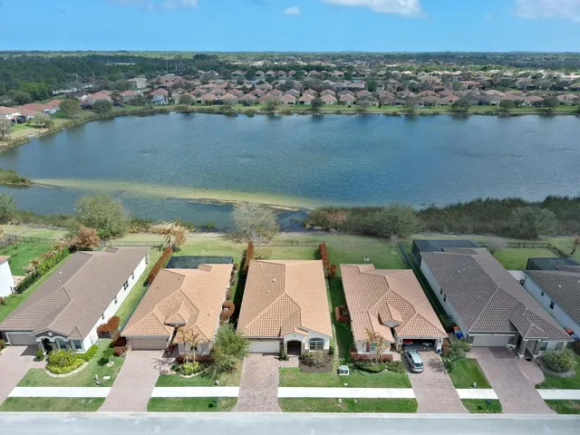 Mediterranean-style residence featuring a tile roof, paver driveway, manicured landscaping, and a waterfront location