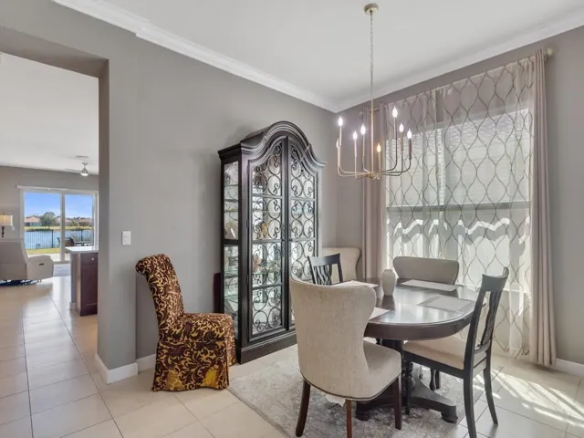 Dining area featuring a modern chandelier, crown molding, and large window with decorative sheers