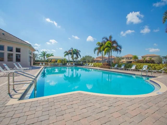 Outdoor swimming pool with integrated steps, surrounded by a brick paver deck and mature landscaping