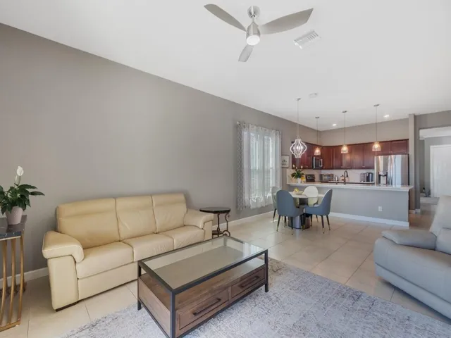 Open-concept living space featuring neutral-toned walls, tile flooring, and a ceiling fan with integrated lighting