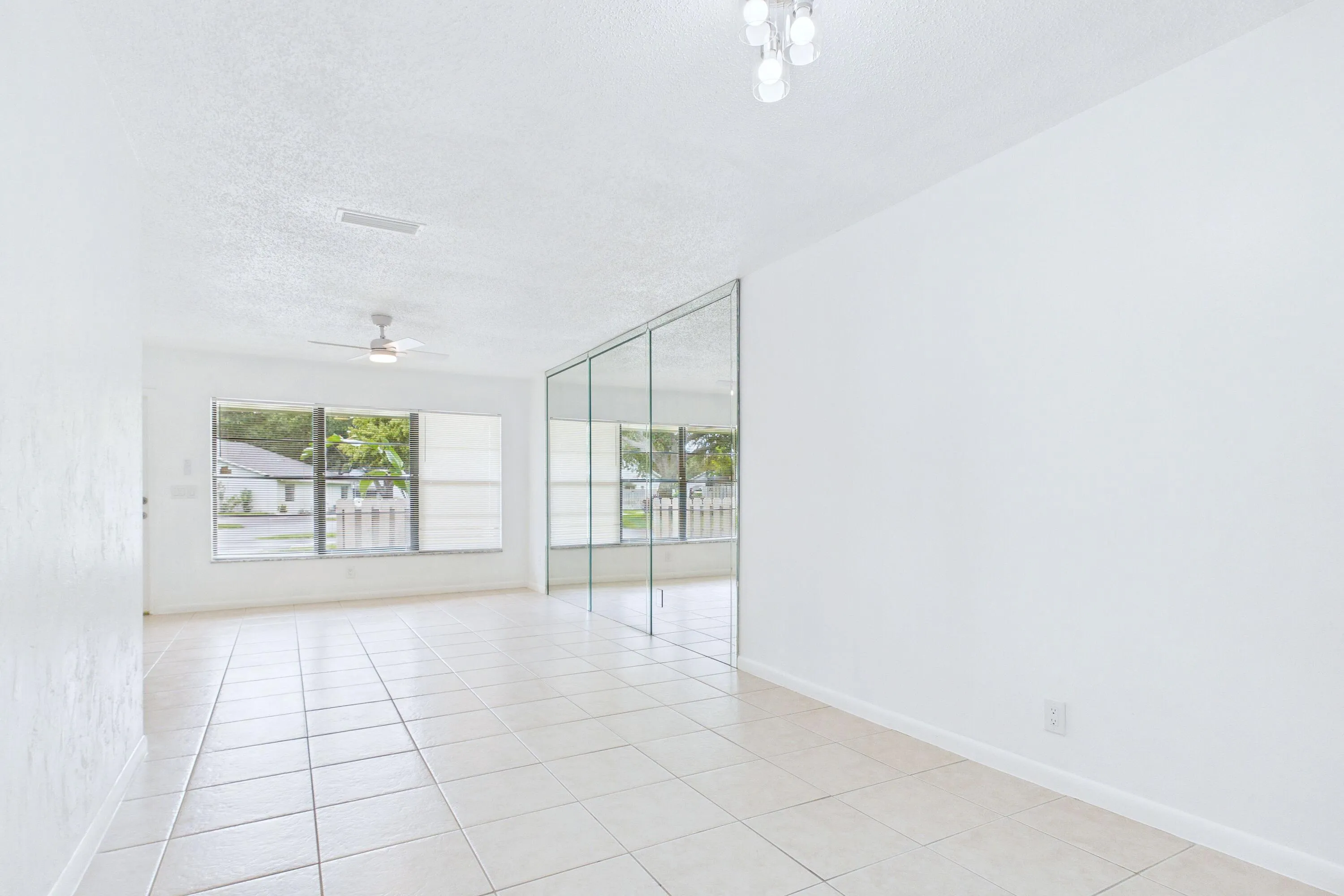 Tile flooring,, ceiling fan with light fixture, window with horizontal blinds, flush mount light fixture