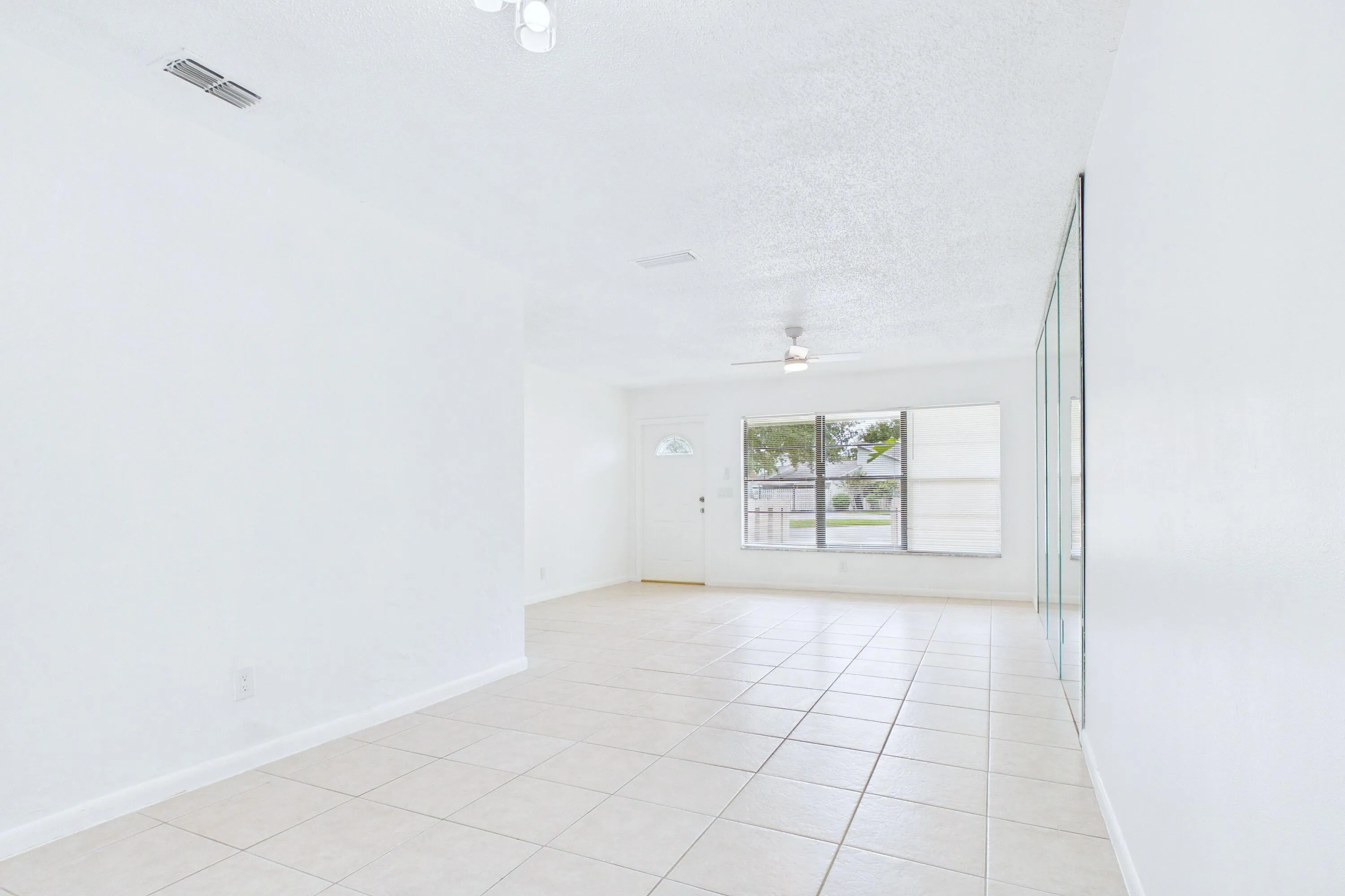 Tile flooring, white walls, ceiling fan, track lighting, mirrored wall panels
