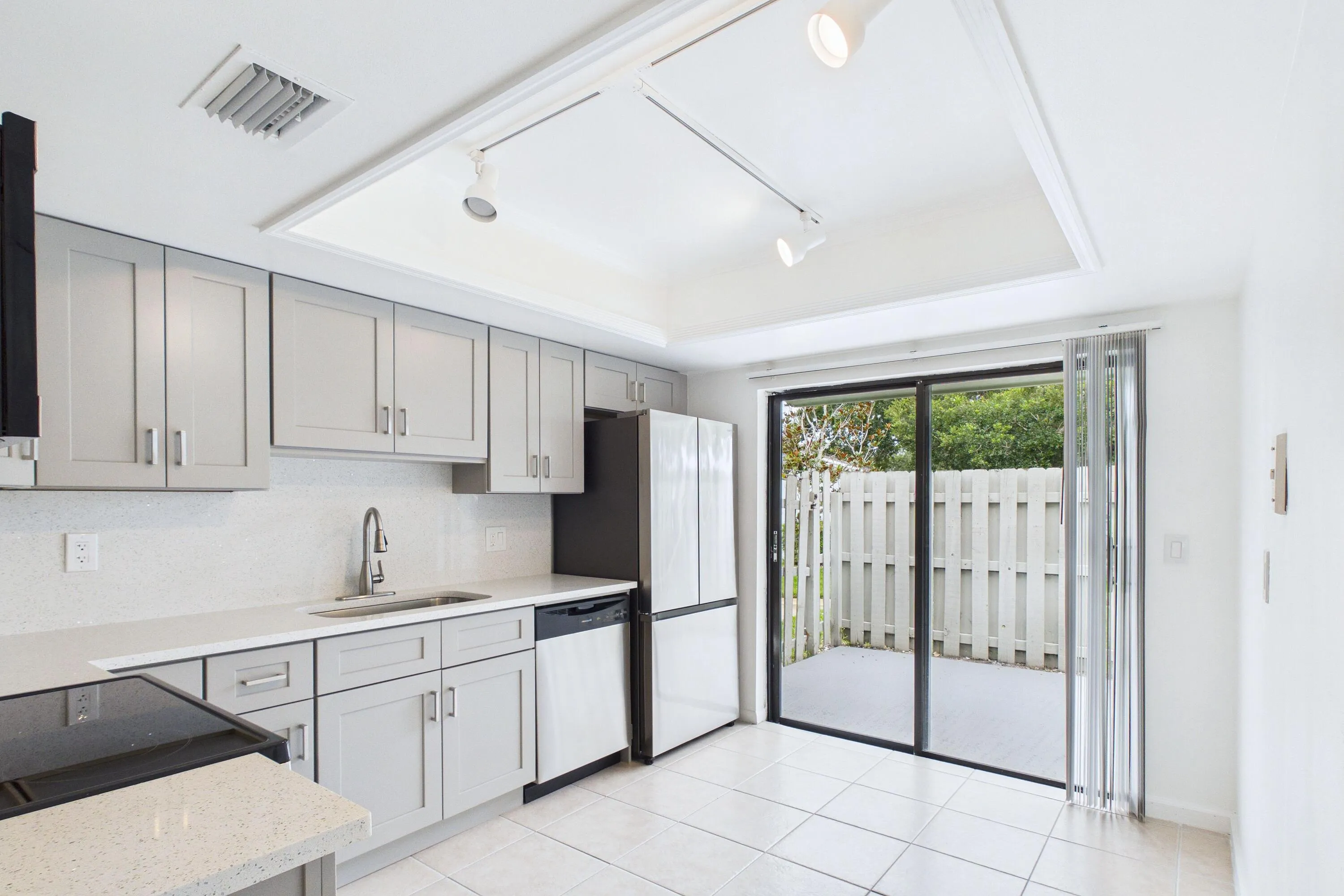 Kitchen with light gray shaker cabinetry, white speckled countertops, a white subway tile backsplash, and a stainless steel sink with a gooseneck faucet