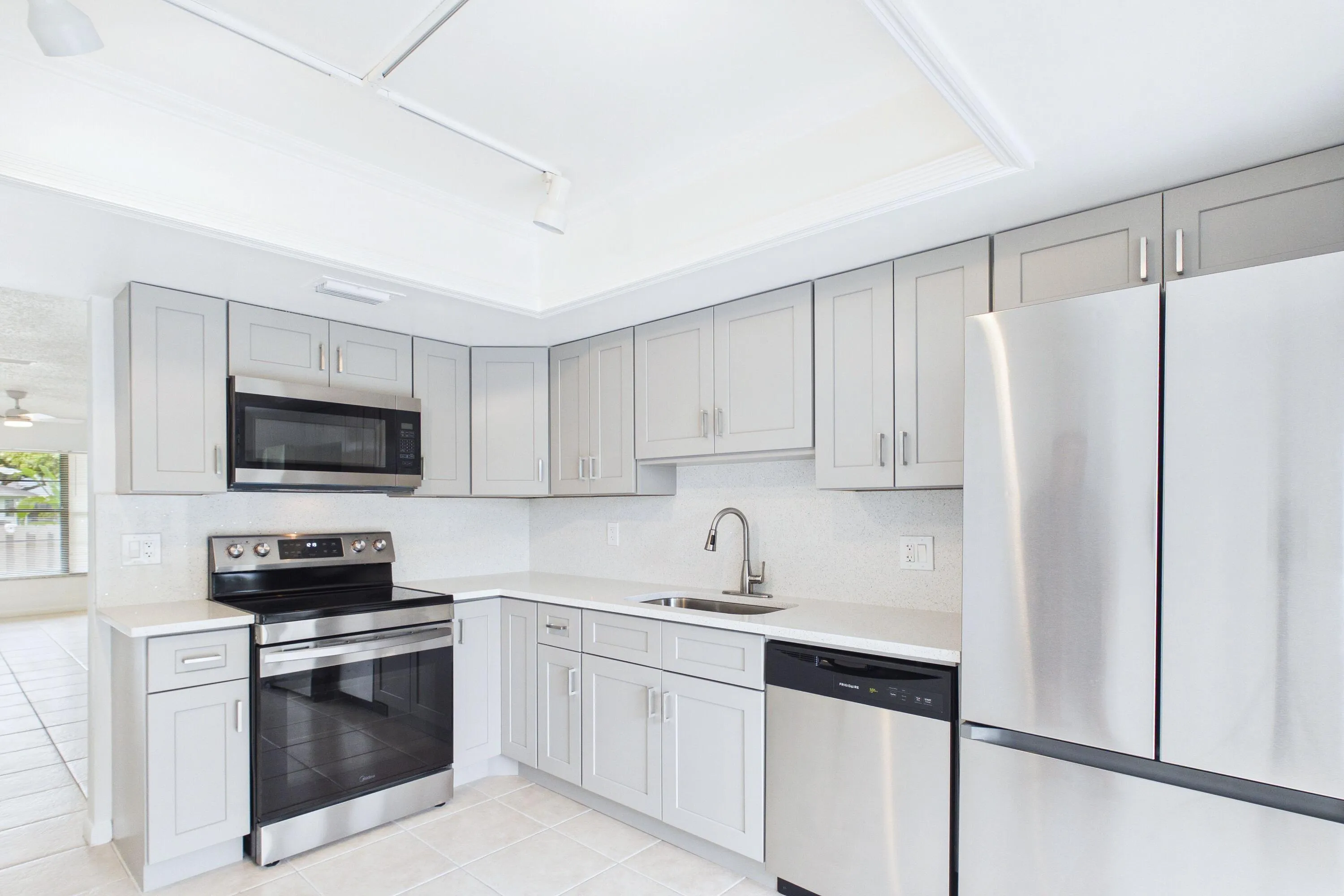 Kitchen featuring light gray cabinetry, stainless steel appliances, white countertops, and tile flooring