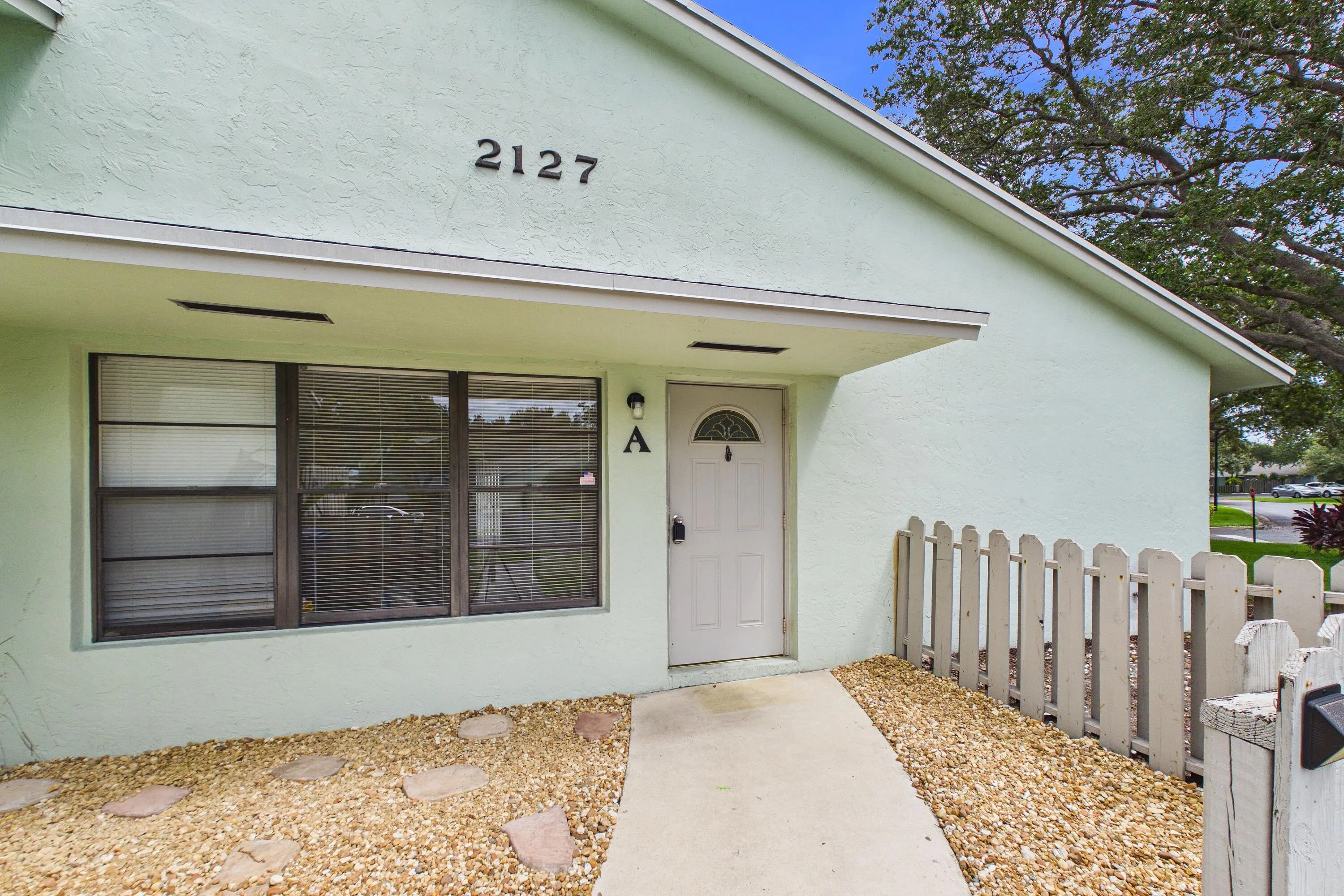 Stucco exterior with a peaked roofline, front entry door with an arched window, and a concrete walkway