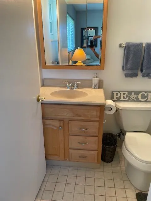 Light wood-finish vanity with a built-in sink, dual-handle faucet, and medicine cabinet