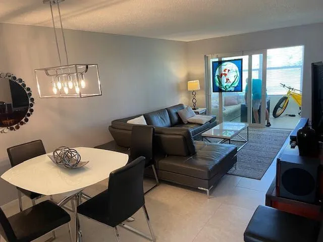 Open-concept living space with tile flooring, a modern rectangular chandelier, and sliding glass doors accessing an outdoor area