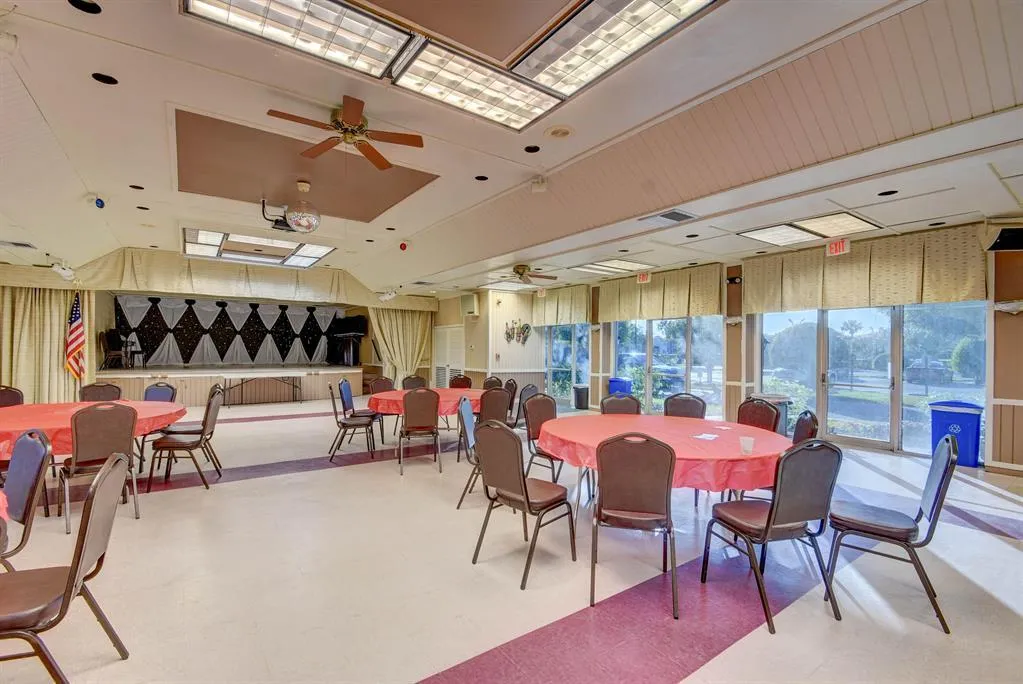 Spacious common area featuring a stage, ceiling fans, recessed lighting, and large windows