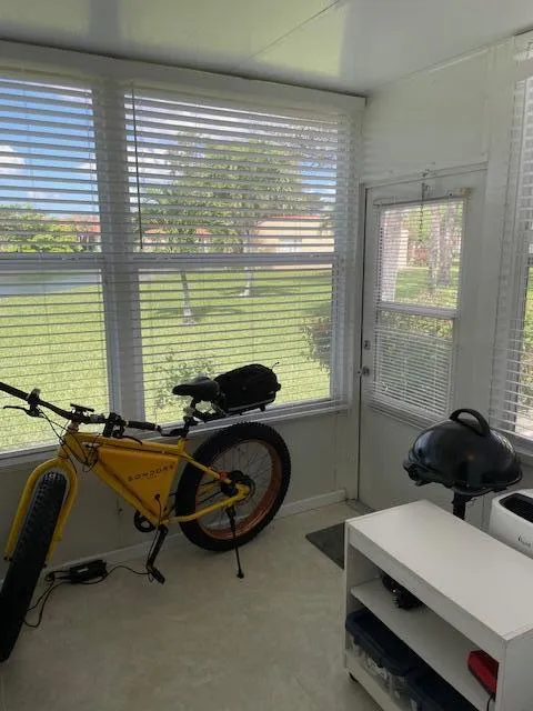 Sunroom with multiple windows, a door with a screen, and light-colored flooring