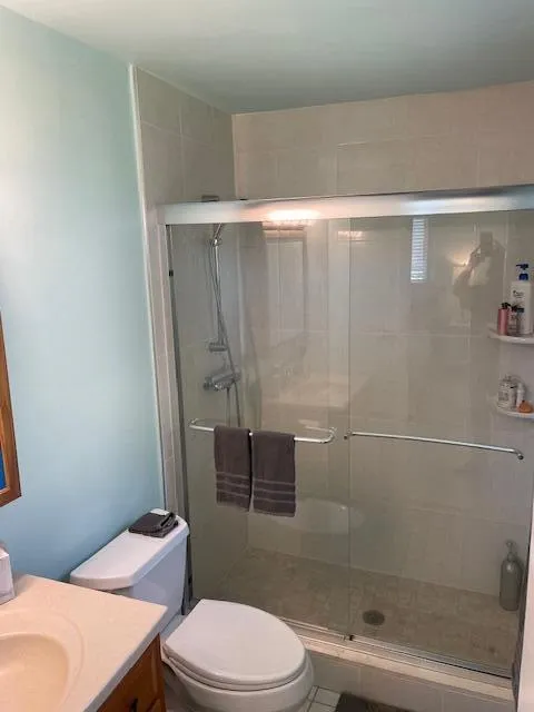 Shower enclosure with sliding glass doors, tiled shower surround, handheld shower fixture, and built-in shelving