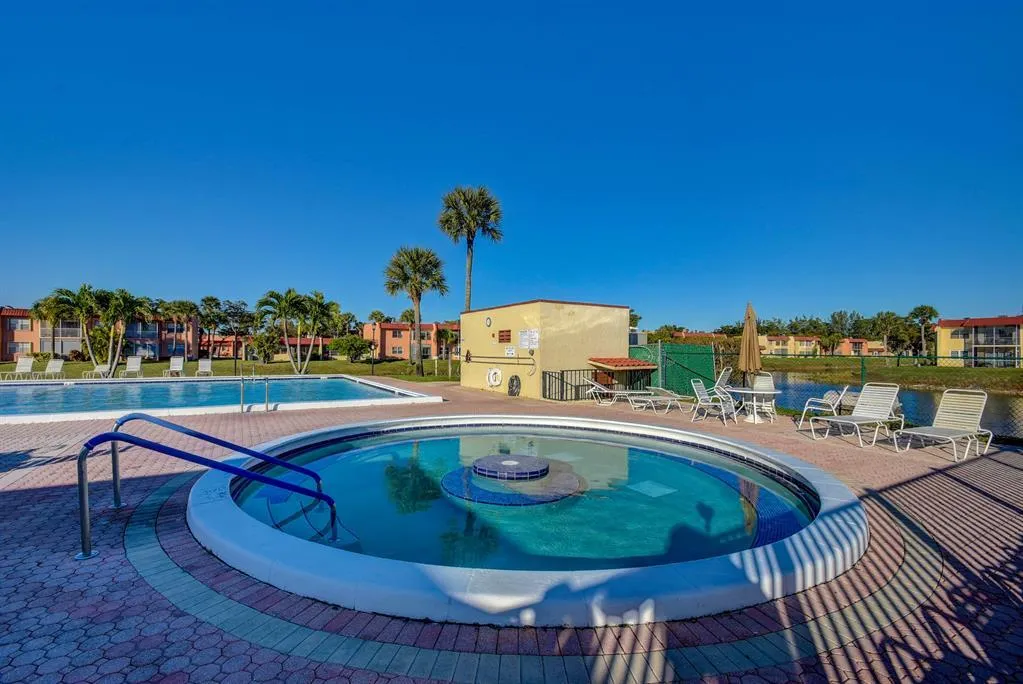 Outdoor spa with a circular design, bordered by a patterned paver deck, adjacent to a rectangular swimming pool