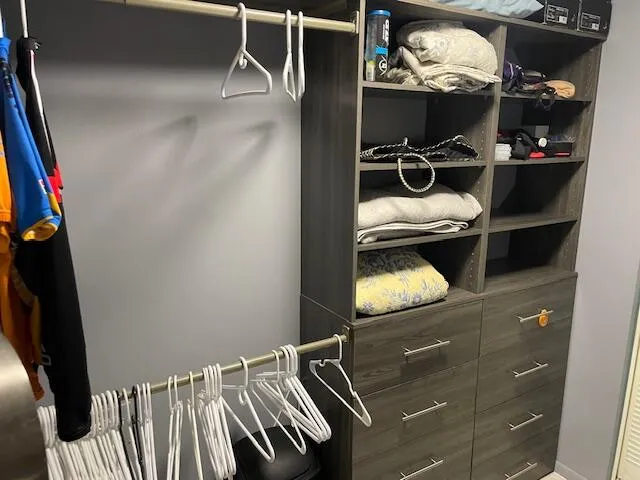 Custom closet system featuring multiple hanging rods, integrated shelving units, and storage drawers with brushed nickel hardware