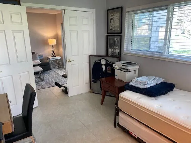 Sliding panel doors, window with blinds, and light-toned tile flooring