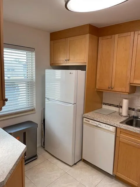 Kitchen featuring wood-finish cabinetry, tile flooring, and a white refrigerator