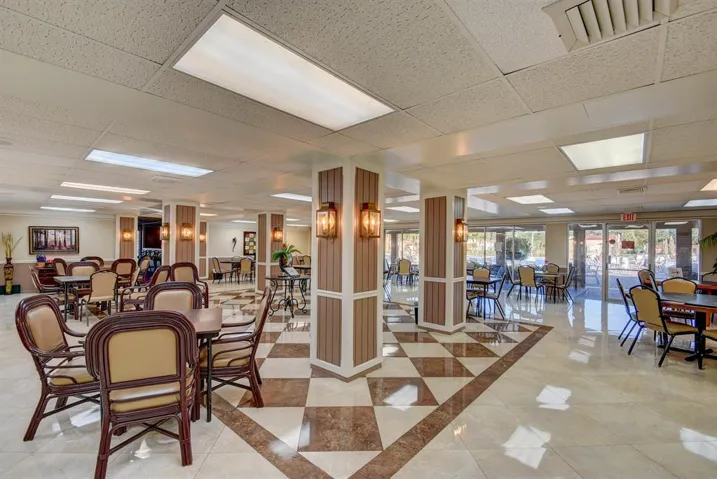 Spacious common area featuring patterned tile flooring, wood-paneled columns with sconce lighting, and recessed ceiling lighting