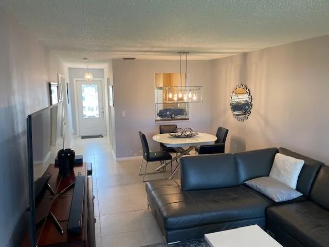 Tile flooring throughout, recessed lighting, and a modern rectangular chandelier over the dining area