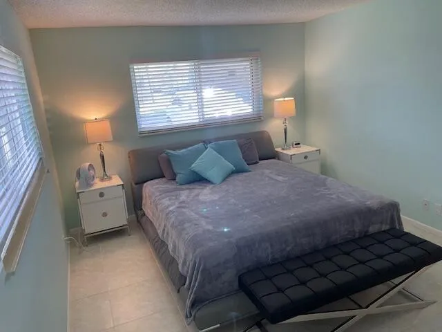 White tile flooring, a window with horizontal blinds, and light-colored walls