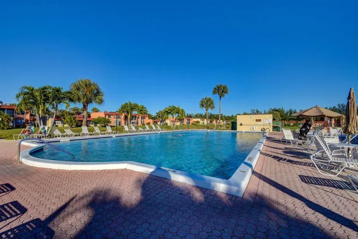 Expansive swimming pool with integrated spa, surrounded by a red paver deck and tropical landscaping