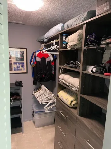 Custom closet system featuring built-in shelving, drawers with brushed nickel hardware, and hanging rod storage