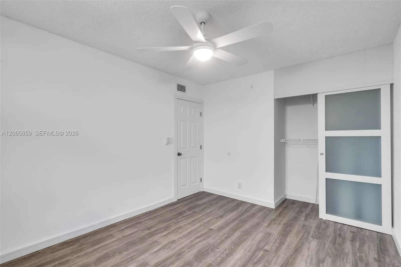 Spacious bedroom featuring ample wall space, and functional sliding closet doors.