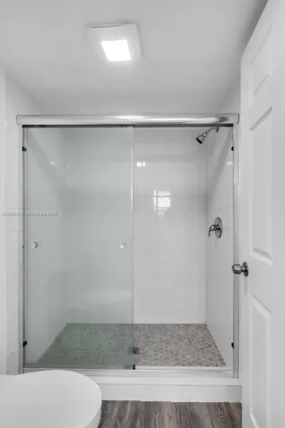 Clean, modern shower design featuring modern glass doors and pristine tiled walls.