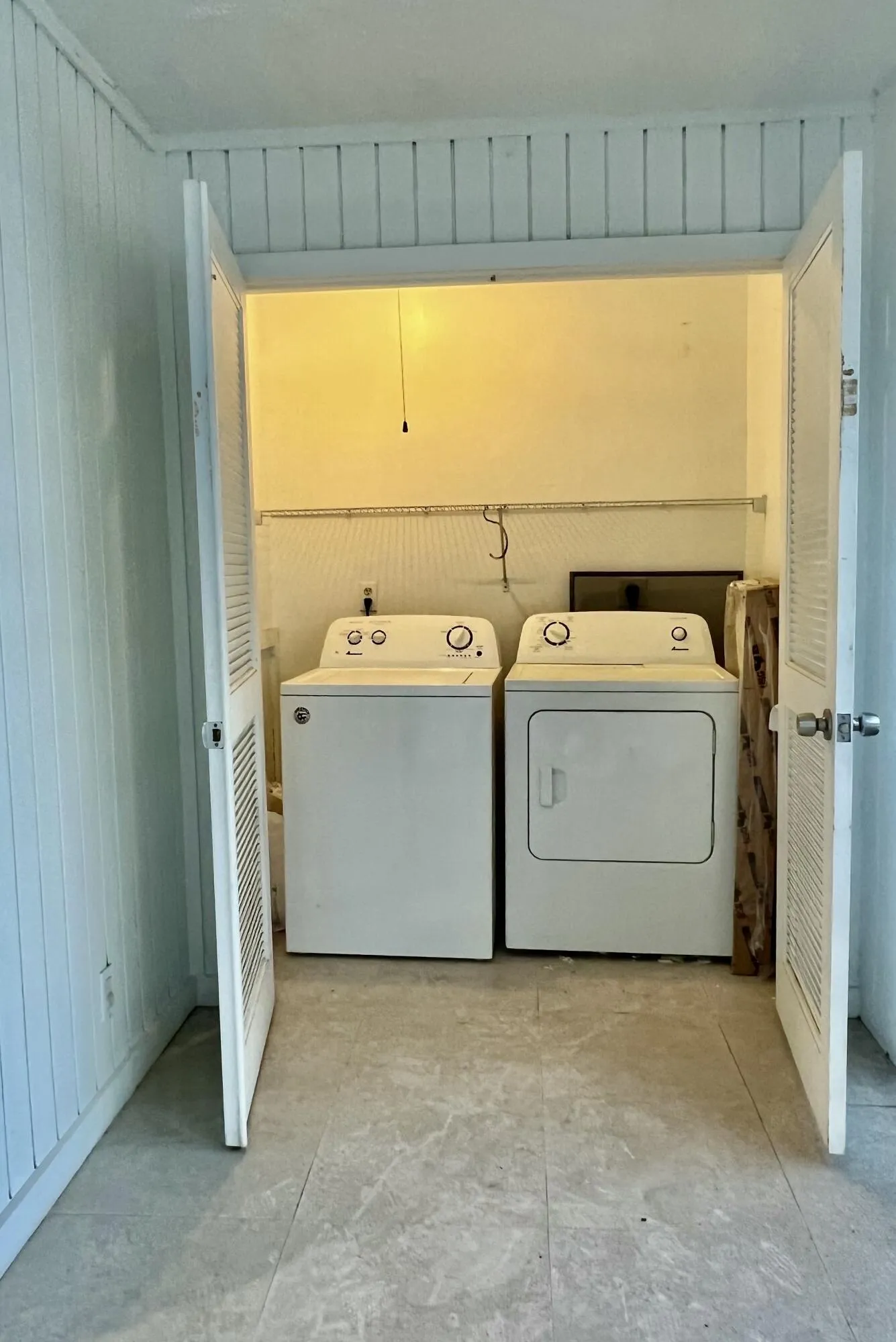 Laundry closet with louvered bi-fold doors and tile flooring