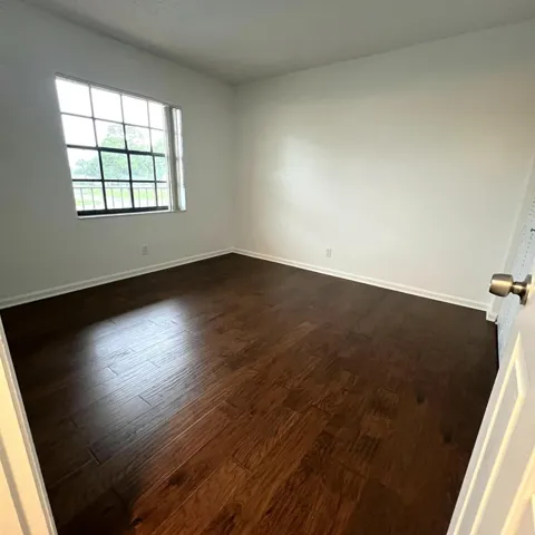 Hardwood-style flooring throughout, white walls, and a multi-pane window