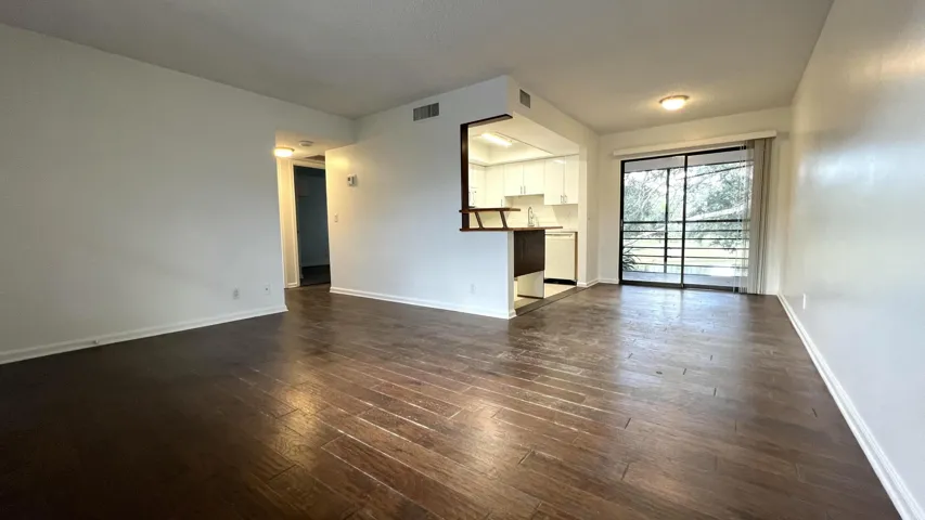 Wood-finish flooring, white walls, and a sliding glass door to an exterior balcony
