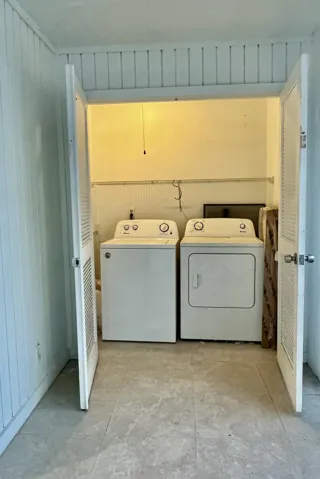 Laundry closet with louvered bi-fold doors and tile flooring