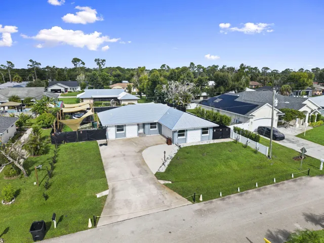 Property featuring a concrete driveway, a white exterior with blue accents, and a light-colored metal roof