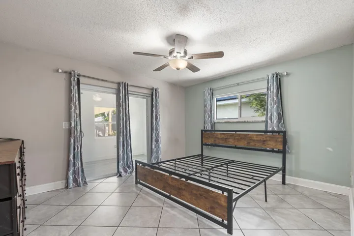 Tile flooring, ceiling fan with integrated lighting, sliding glass doors, and a window for natural illumination