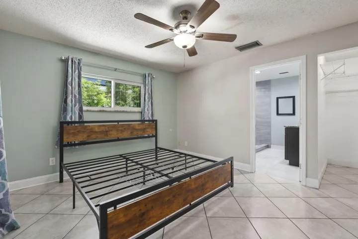 Tile flooring, ceiling fan with integrated lighting, built-in closet shelving, and an en-suite bathroom with a vanity