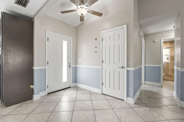 Tiled flooring, vaulted ceiling, ceiling fan, white paneled doors, and two-tone wall treatment