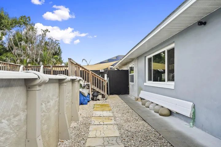Rear exterior with stucco siding, white-framed windows, and an above-ground pool