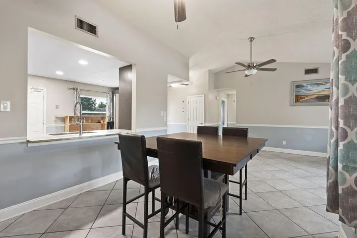 Tray ceiling, ceiling fan, tile flooring, pass-through window, and chair rail molding