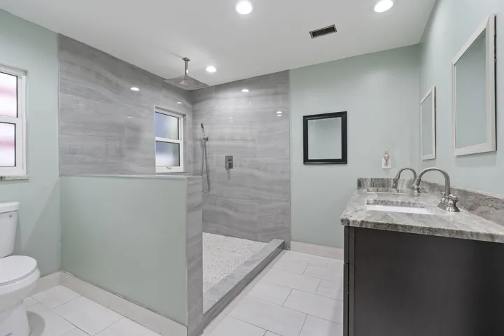Walk-in shower with large format wall tile, rain shower head, and mosaic tile flooring