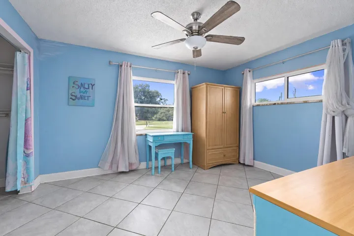 Tile flooring, ceiling fan with light fixture, and multiple windows