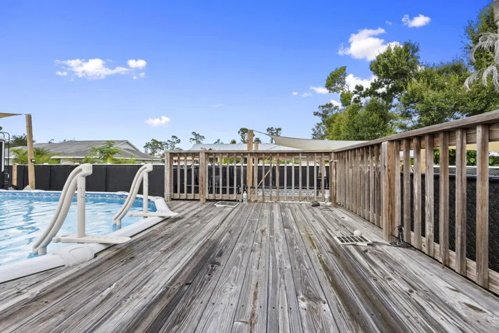 Expansive wood deck with a built-in above-ground pool, featuring a sturdy wooden railing and integrated pool steps